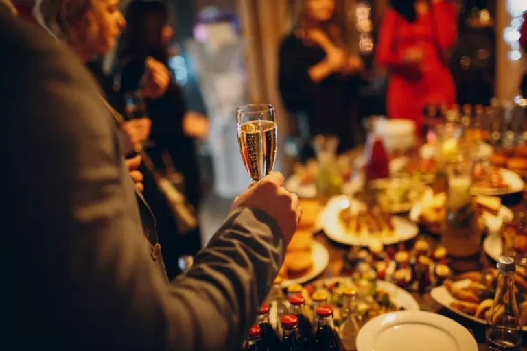 A person holding a glass of champagne at a holiday party.