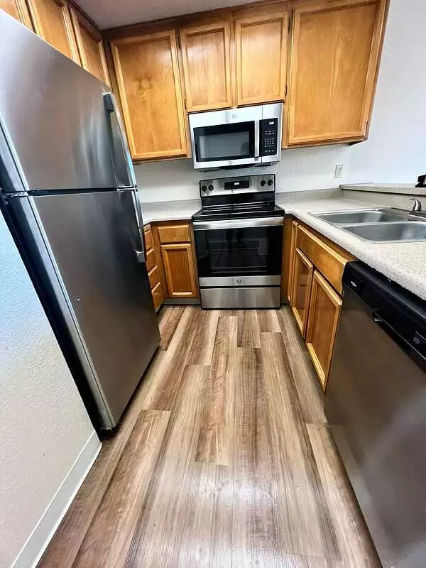 A kitchen with stainless steel appliances and wood floors.