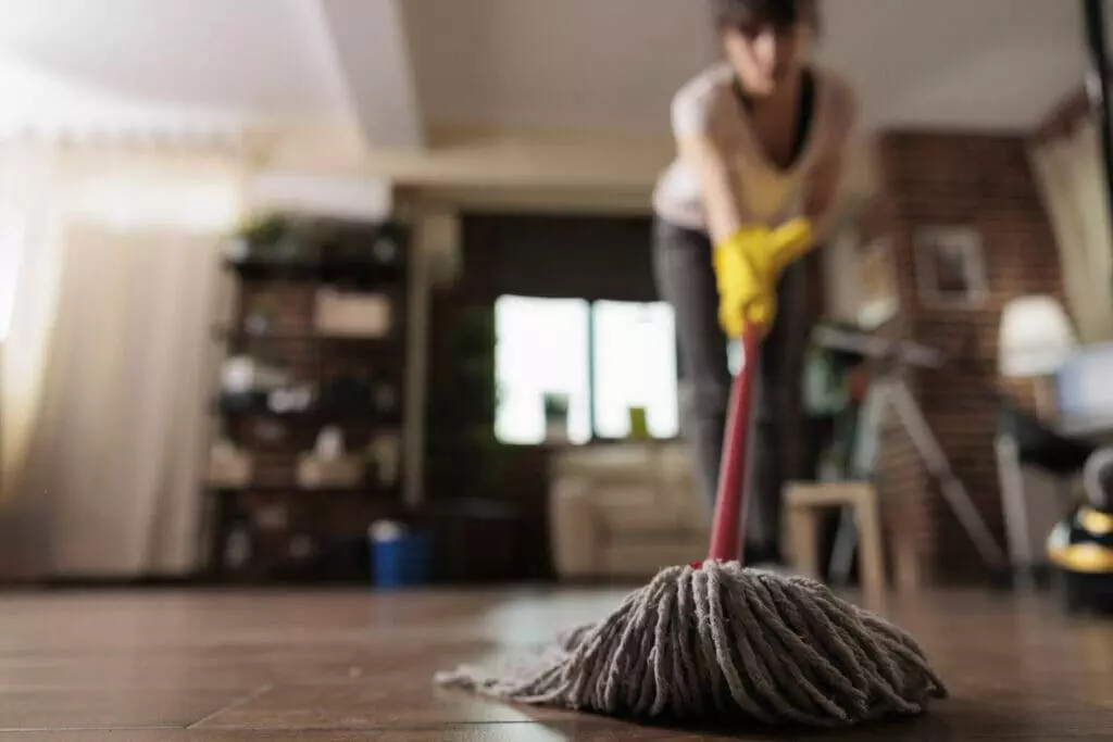 A woman cleaning the floor in a living room.