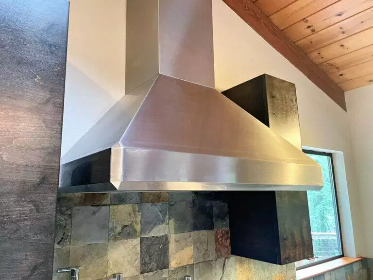 A stainless steel range hood in a kitchen requiring master clean.