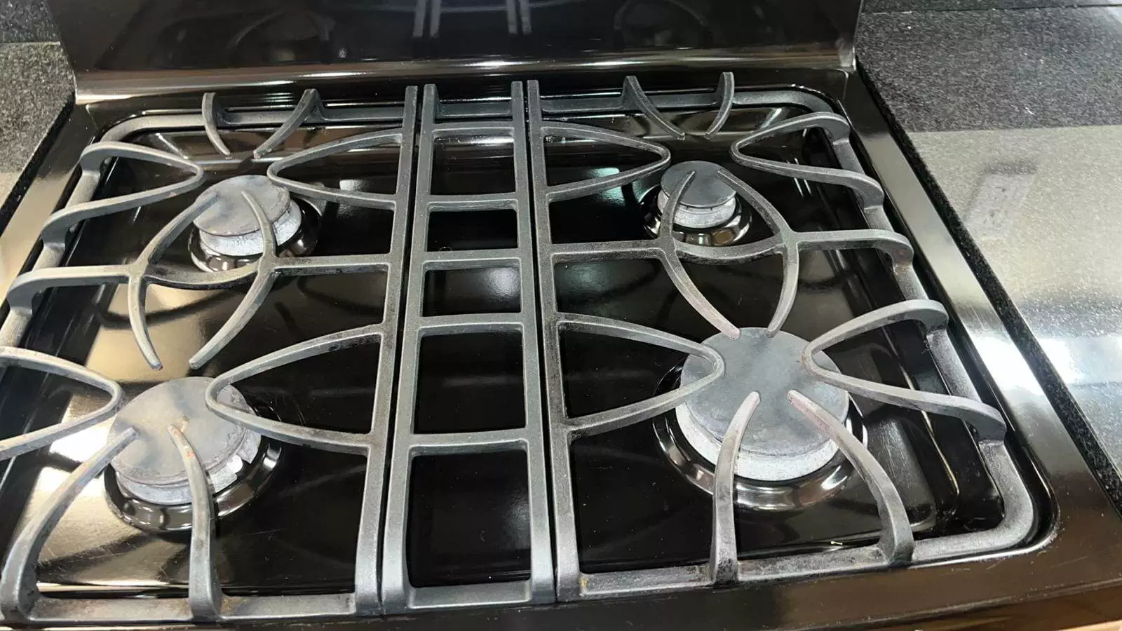 A stove top with four burners, needing a move-out clean in the kitchen.