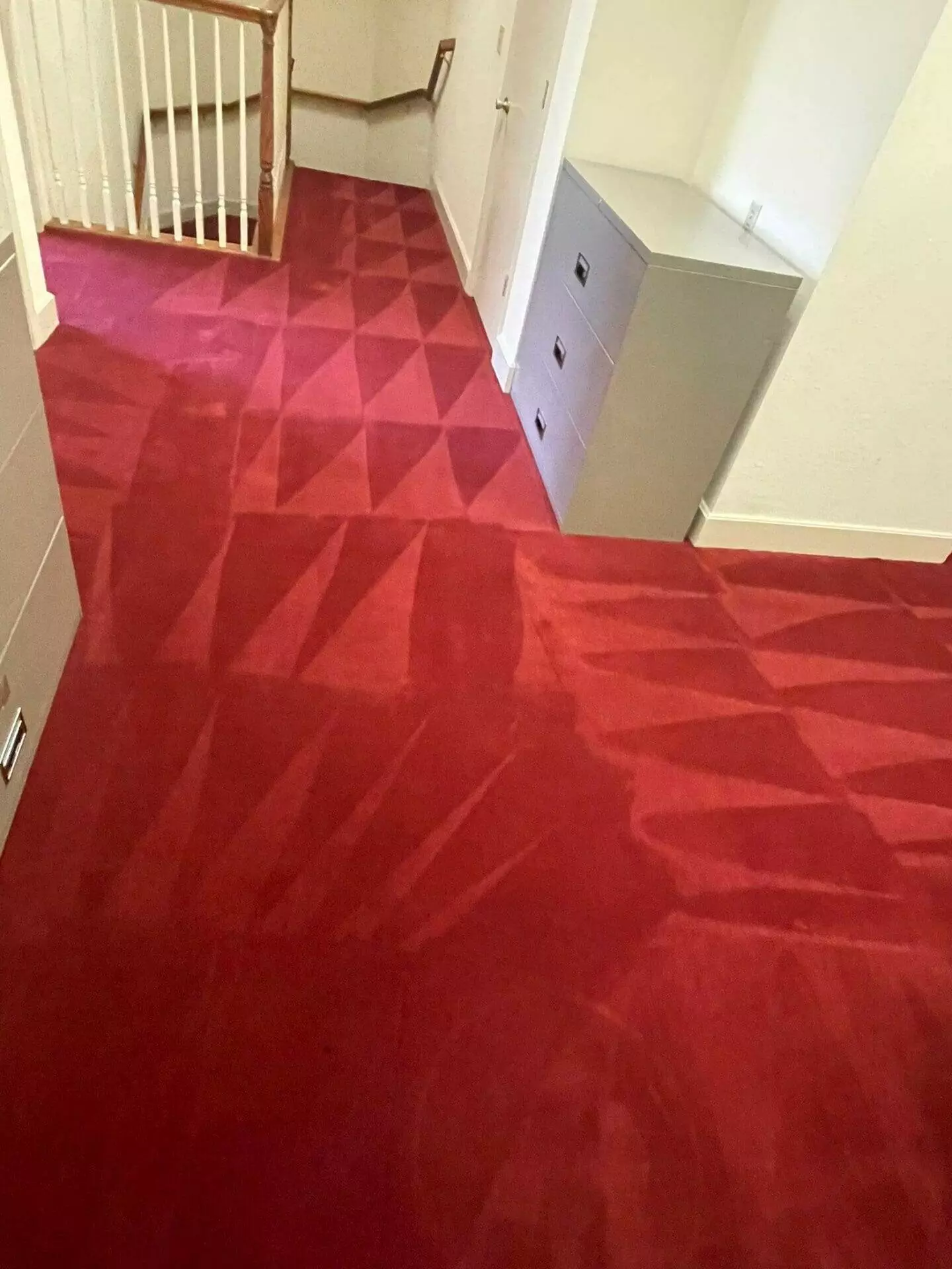 A carpeted red room with stairs.