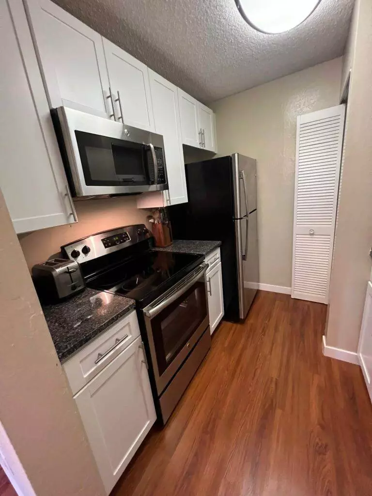 A clean kitchen with stainless steel appliances and hardwood floors for Airbnb and property management purposes.