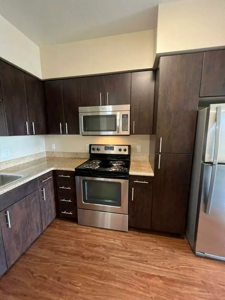 Keywords: kitchen, cabinets, appliances. 

A kitchen with brown cabinets and stainless steel appliances.