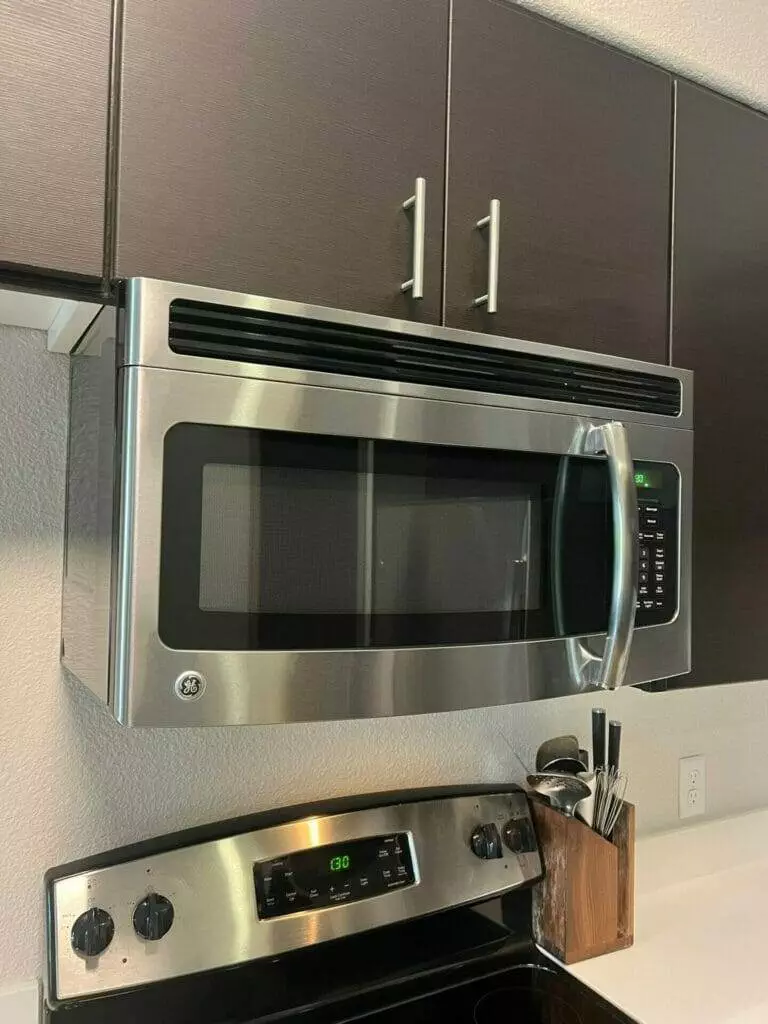 A microwave is hanging above a stove in a kitchen.