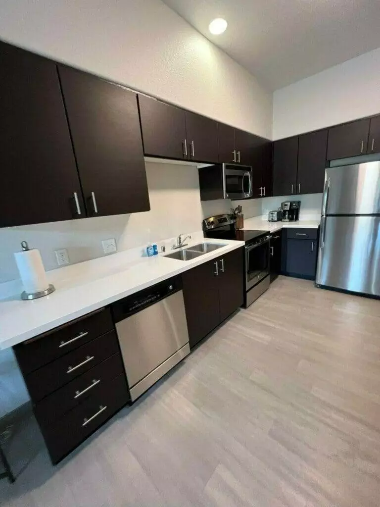 A kitchen with black cabinets and stainless steel appliances.