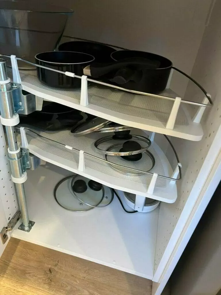 A kitchen cabinet with pans and pots in it.
