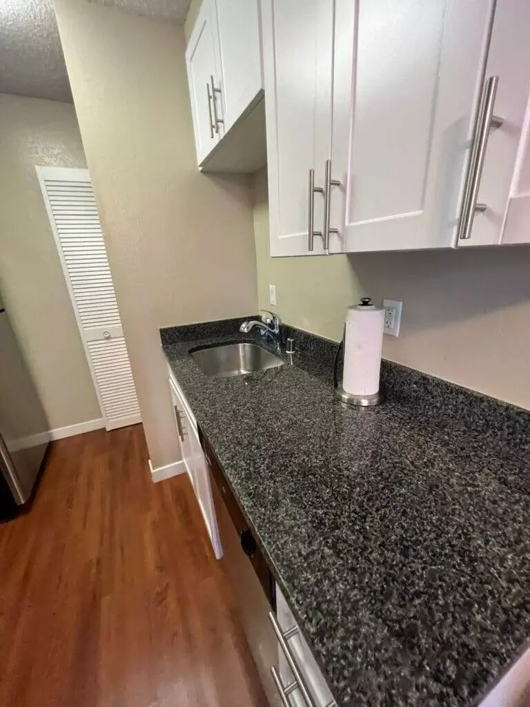 A mid-term rental kitchen with granite counter tops and stainless steel appliances.
