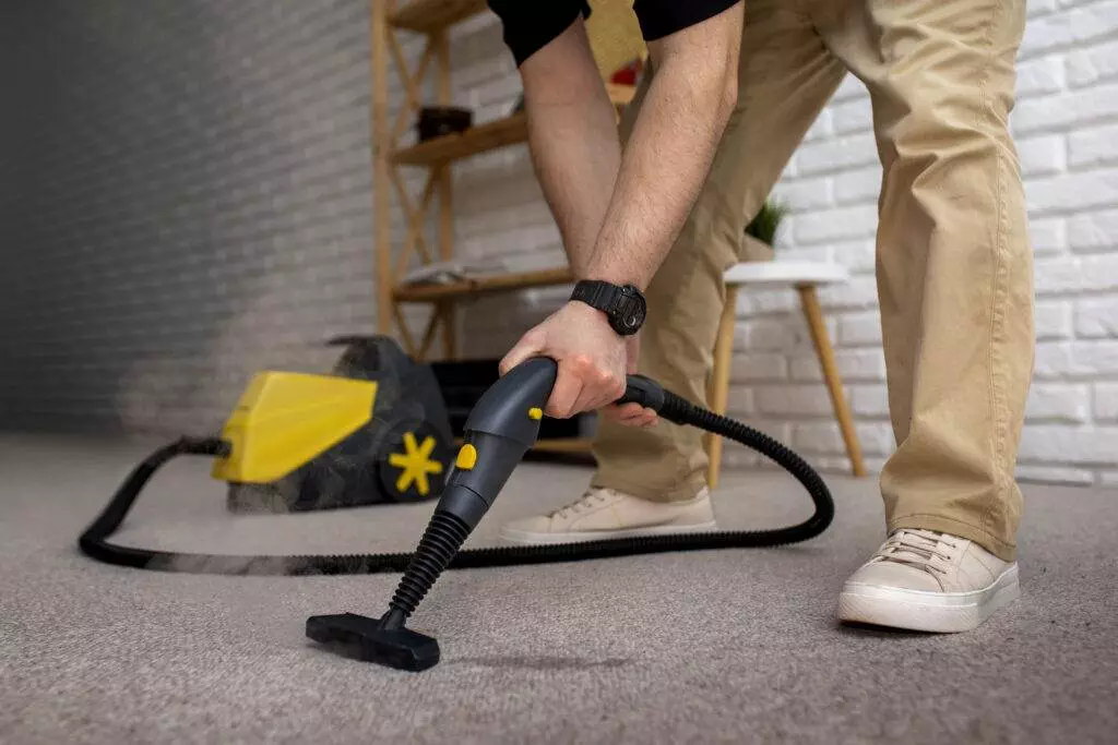 A man using a vacuum cleaner on a carpet in his living space in San Jose.