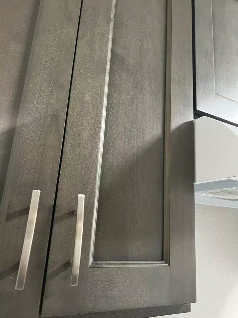 Close-up of a modern kitchen cabinet with gray wood texture and spotless finish.