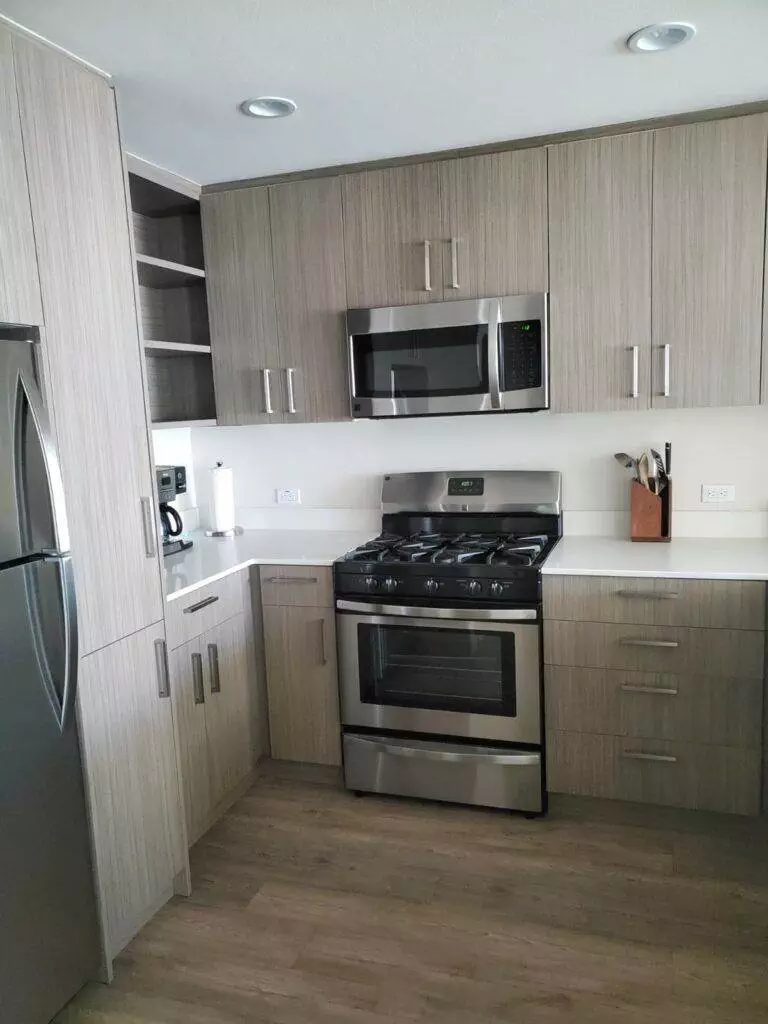 A modern kitchen with wood grain cabinets, stainless steel appliances, and gray flooring offers customized cleaning plans to meet all your needs.