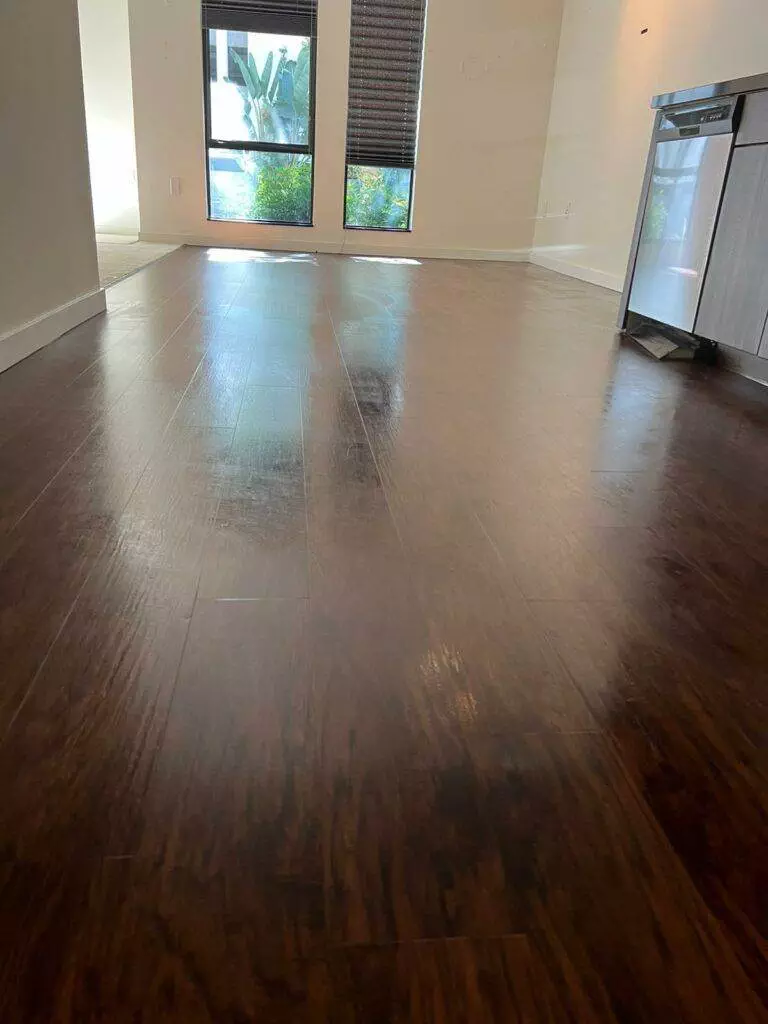 Empty room with polished wooden flooring and large windows showing lush greenery outside, ready for a San Jose Move In / Out Cleaning.