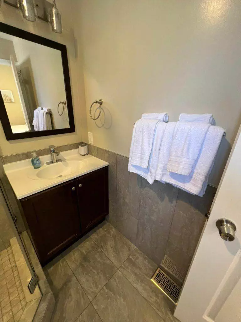 A small bathroom featuring a white sink with a Master Clean Service wooden vanity, a mirror above, and white towels hanging on the wall to the right.