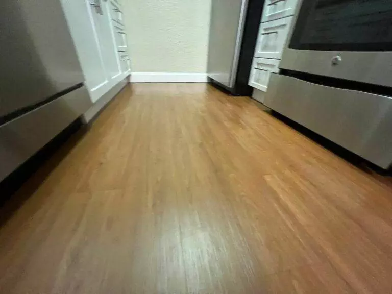 A kitchen hallway featuring wooden flooring with stainless steel appliances on either side, ready for a Campbell Move in / Out Cleaning transition.