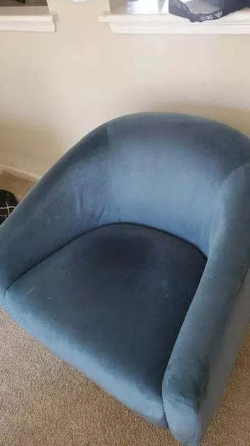 A blue fabric armchair with visible wear marks, revitalized by Fremont Upholstery Cleaning, placed on a carpeted floor in a room.