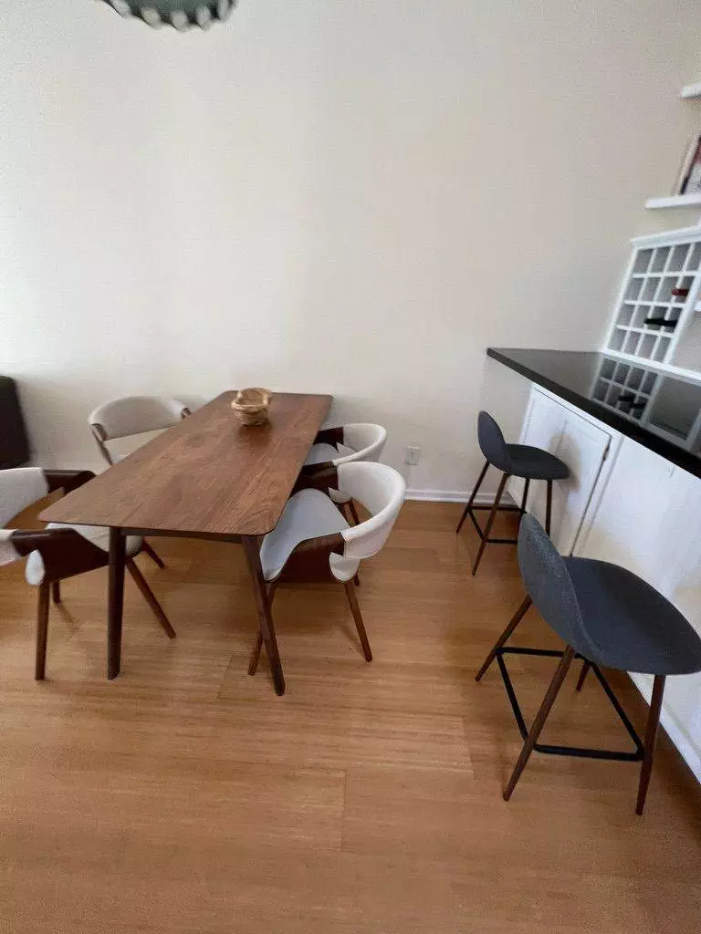 A modern dining room featuring a wooden table with white and dark chairs, and a shelving unit that just underwent a Furniture Revitalization in the background.