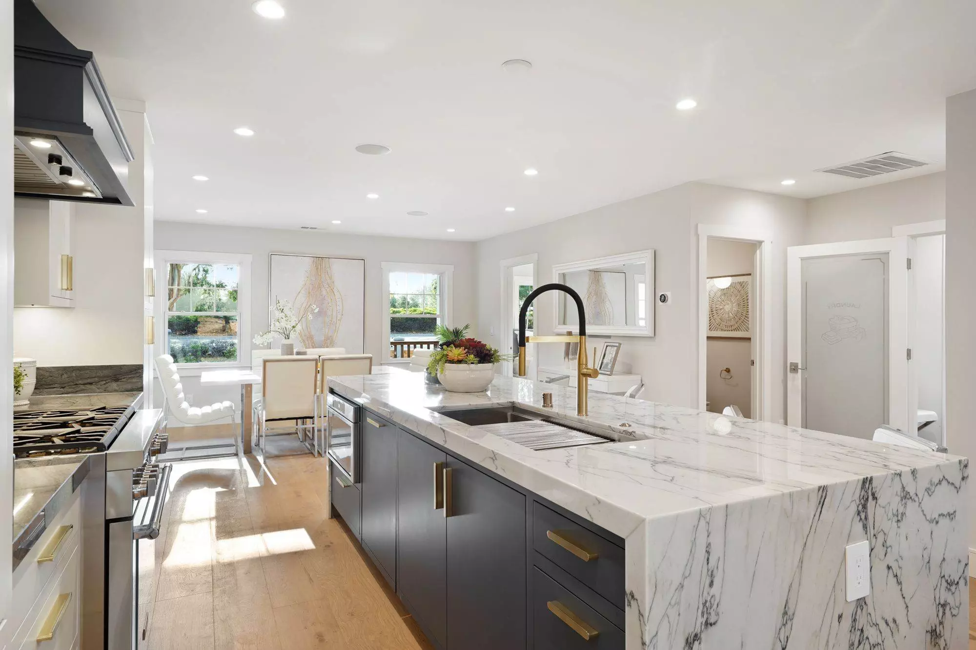 Modern kitchen interior with marble countertops, stainless steel appliances, and an open layout leading to a dining area with natural light, perfect for a construction portfolio showcase.