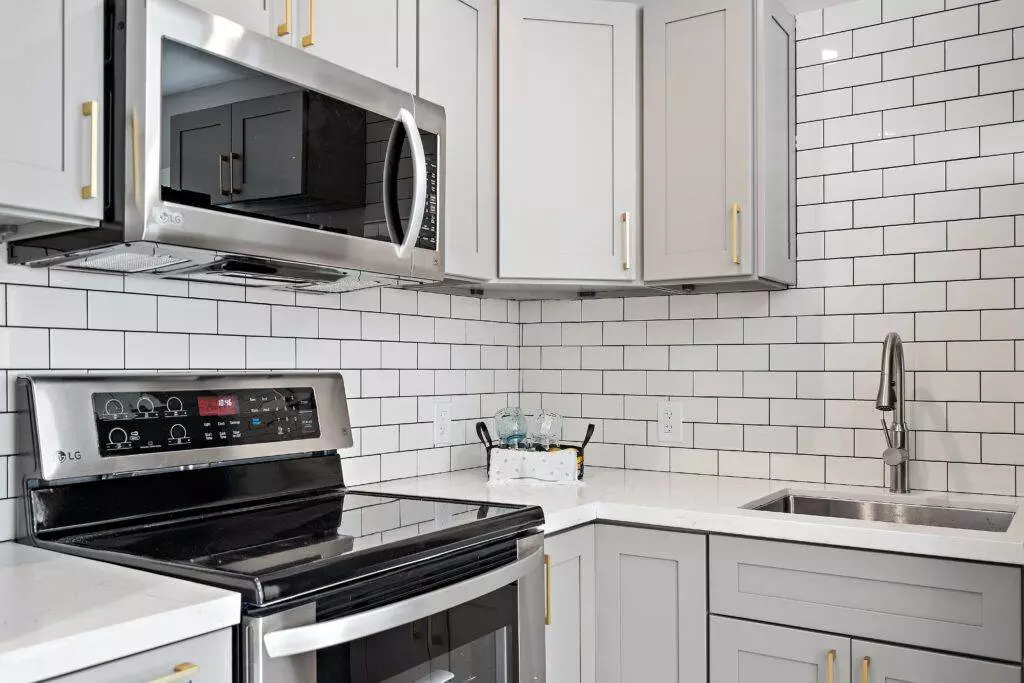 Modern kitchen interior with white subway tile backsplash, gray countertops, and stainless steel appliances, ideal for a post-construction portfolio.